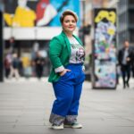 Pewna siebie kobieta plus size w modnym stroju stoi na ulicy miejskiej w jasnym świetle