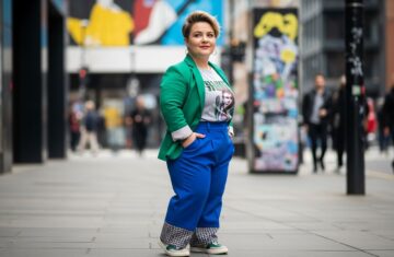 Pewna siebie kobieta plus size w modnym stroju stoi na ulicy miejskiej w jasnym świetle