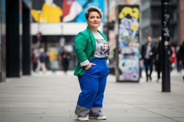 Pewna siebie kobieta plus size w modnym stroju stoi na ulicy miejskiej w jasnym świetle