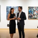 Elegancka para rozmawia podczas wieczornego wernisażu w nowoczesnej galerii sztuki.