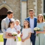 Rodzina w eleganckich strojach uczestniczy w komunii przed kościołem wiosną, naturalne światło, radość